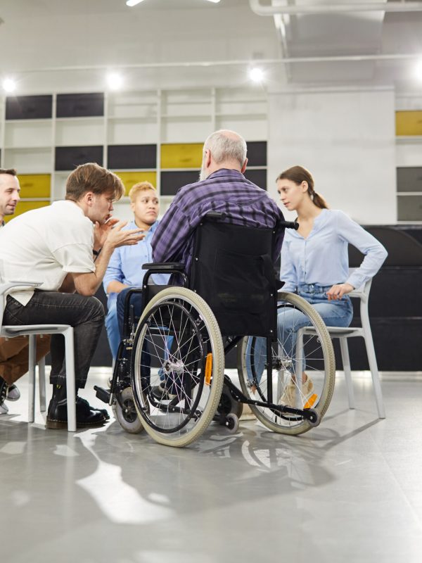 Back view portrait of handicapped man sharing troubles with support group during therapy session, copy space